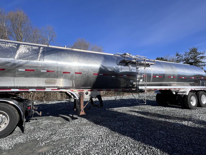 Long side view of the tanker trailer under a blue sky.